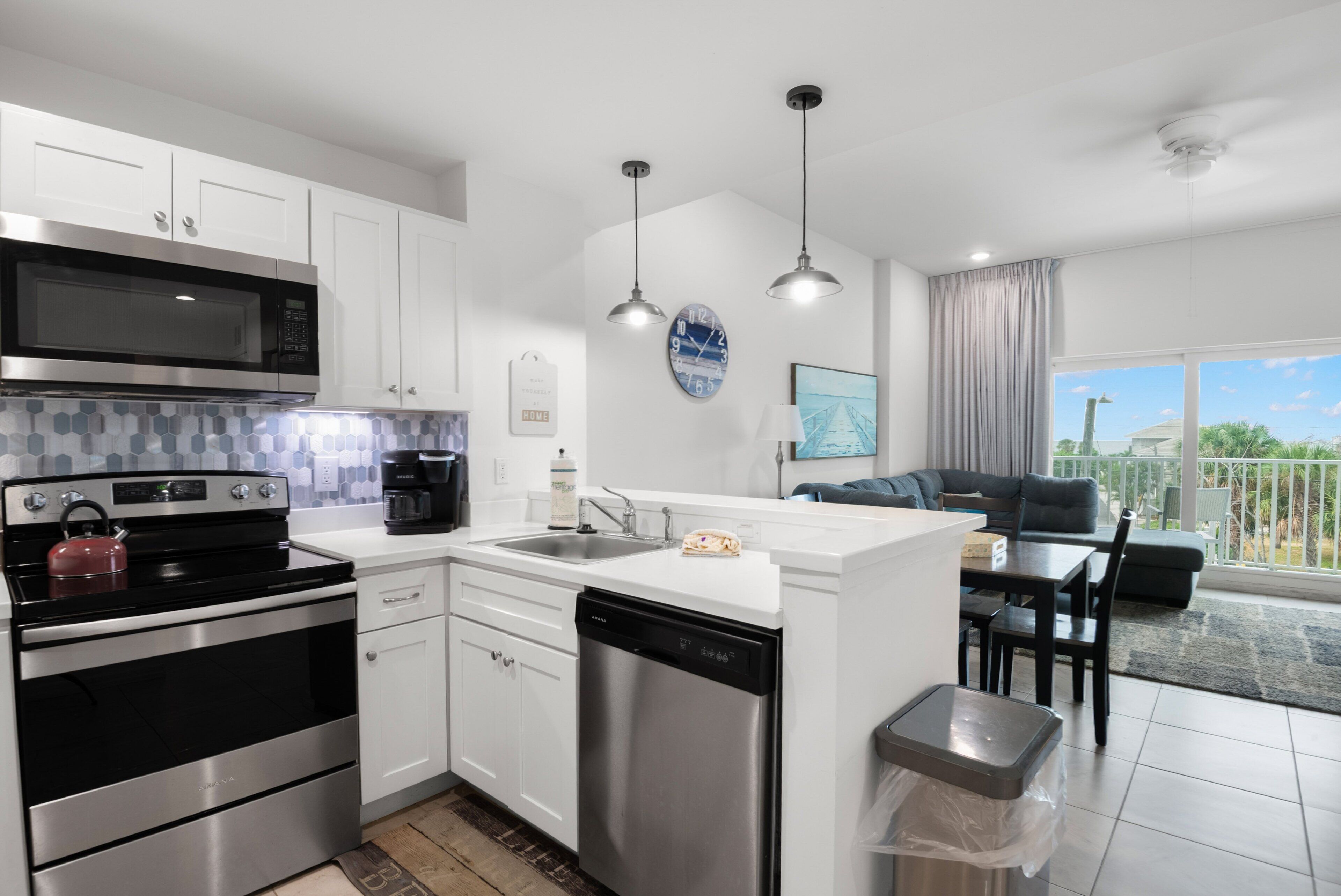 A modern kitchen with stainless steel appliances, a dishwasher, and a dining area with a view.