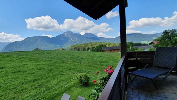 Ein Balkon mit Blick auf ein grünes Feld und Berge.