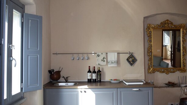 A kitchen with a wooden countertop, a sink, and wine bottles. - Agriturismo La Posta Reale (Castiglion Fibocchi)