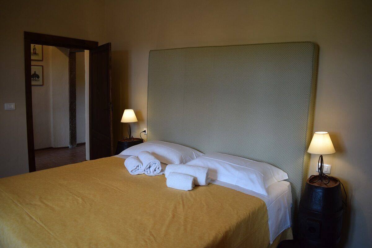 Ein Hotelzimmer mit einem großen Bett, zwei Nachttischlampen und einer Tür zu einem anderen Raum.