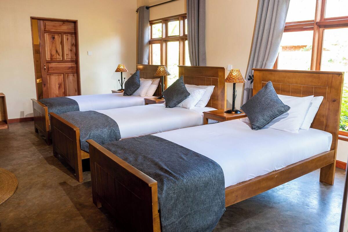 A hotel room with two wooden beds, each with a headboard, a nightstand, and a lamp.