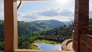 Vista desde un balcón sobre una piscina y colinas verdes exuberantes.
