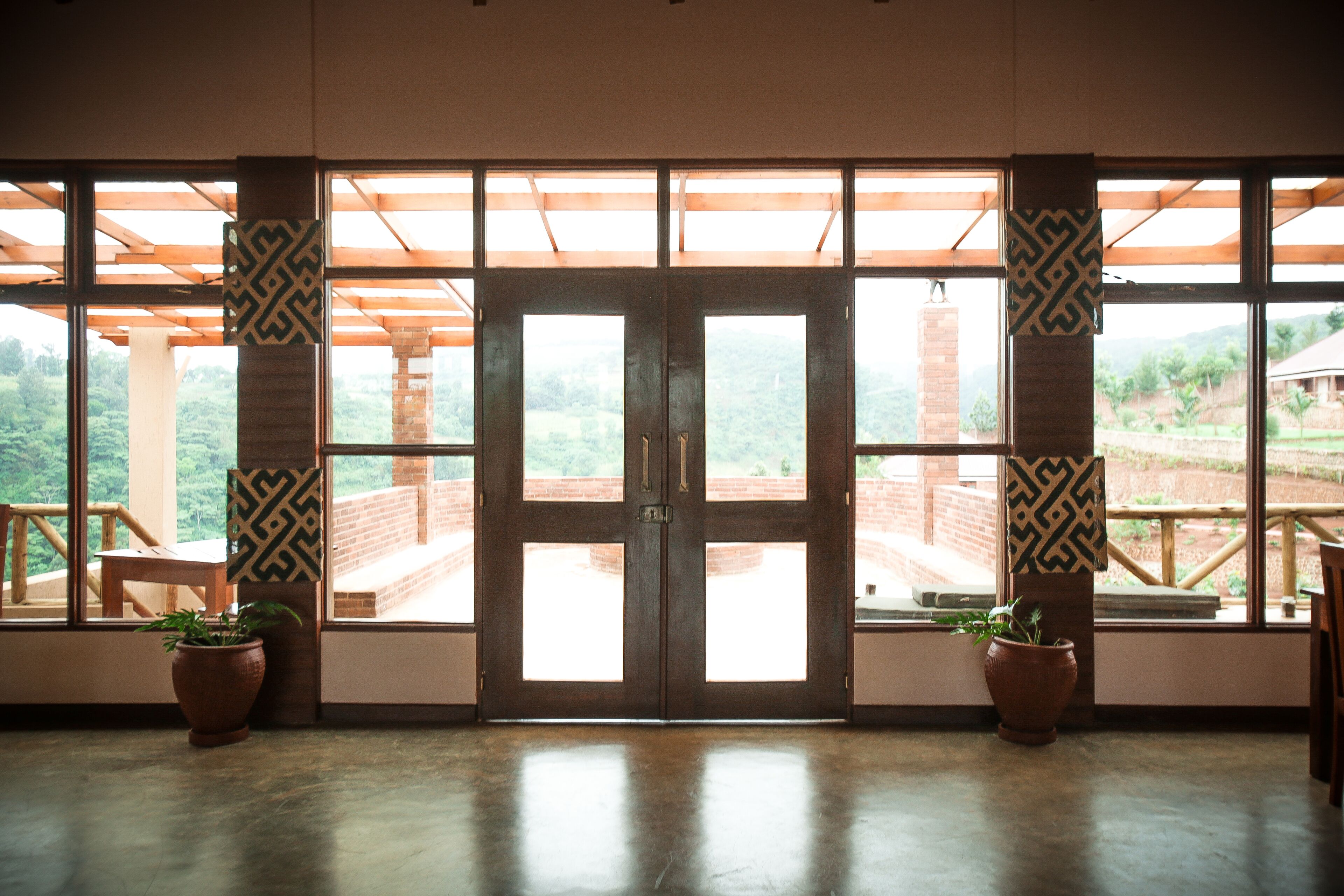 A large wooden door with a view of a brick structure and greenery outside.