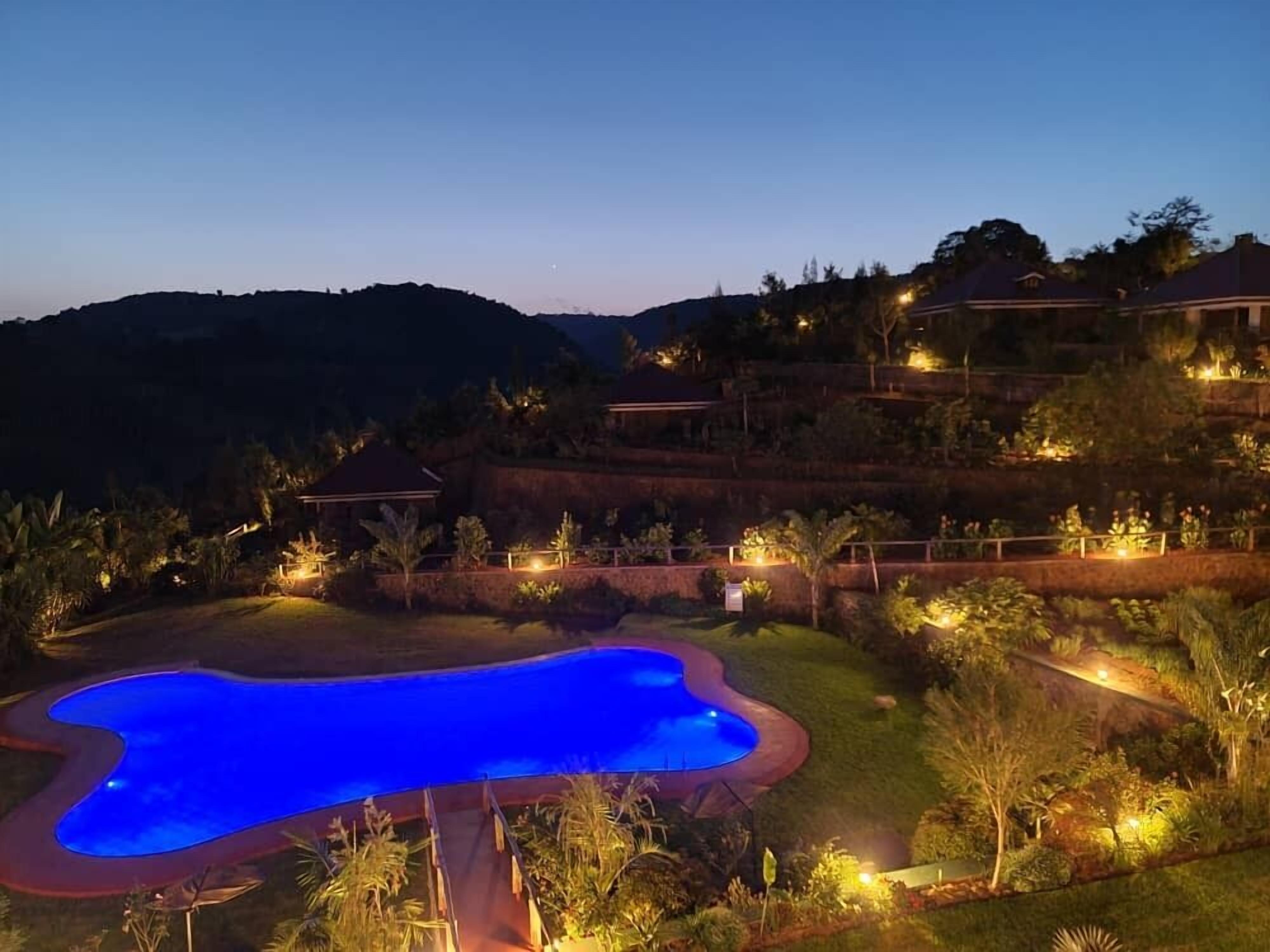 A swimming pool surrounded by a landscaped garden with a view of hills in the background.