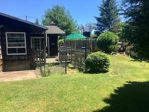 Enjoy a peaceful retreat in this charming backyard with a porch, chimney, and lush greenery.