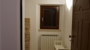 En smal gang med en radiator, et vindue og en dør.