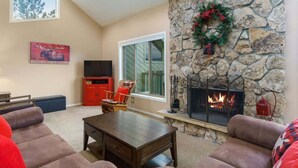 Una sala de estar acogedora con chimenea de piedra, asientos cómodos y un televisor.