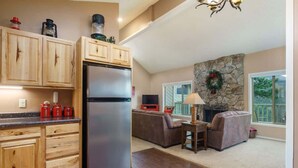 Una cocina moderna con armarios de madera, un refrigerador de acero inoxidable y una chimenea de piedra.