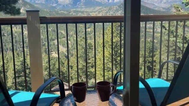 Un balcón con mesa y sillas, con vista a un paisaje montañoso.