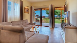 A modern living room with a sofa, a small round table with a bottle and glass, and a TV on a stand. - Holiday Home Sea - Two Bedroom Beach House (Petrovac)