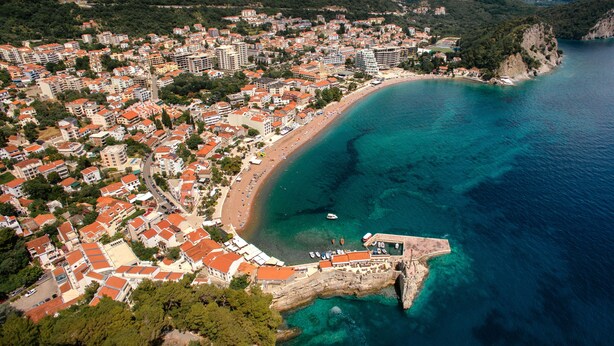An aerial view of a coastal town with a beach, buildings, and a rocky coastline. - Holiday Home Sea - Two Bedroom Beach House (Petrovac)