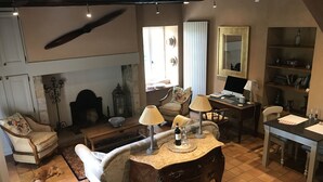 Un accogliente soggiorno con camino, zona pranzo e angolo studio con computer.