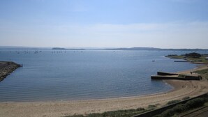 A coastal view with a sandy beach, calm water, and boats. - Beach Point - Stunning Harbour Views from Balcony (Poole)