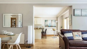 Ein modernes Wohnzimmer mit einer braunen Ledersofa, einem Esstisch mit Stühlen und einer Küchenzeile im Hintergrund.