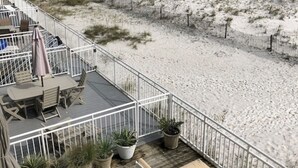 A deck with outdoor seating and potted plants, overlooking a beach with a fence and dunes. - WOW Closest to the Gulf Luxury 4 Bed,3Bath 3 Decks Sleeps 14 2500 SF (Pensacola Beach)