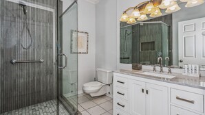 A modern bathroom with a glass-enclosed shower, a white toilet, and a vanity with a large mirror and multiple light fixtures. - WOW Closest to the Gulf Luxury 4 Bed,3Bath 3 Decks Sleeps 14 2500 SF (Pensacola Beach)