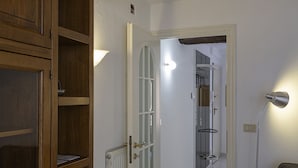 Een gang met een houten garderobe, een radiator en een wandlamp.