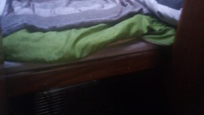 A bunk bed with a green blanket and a patterned blanket.
