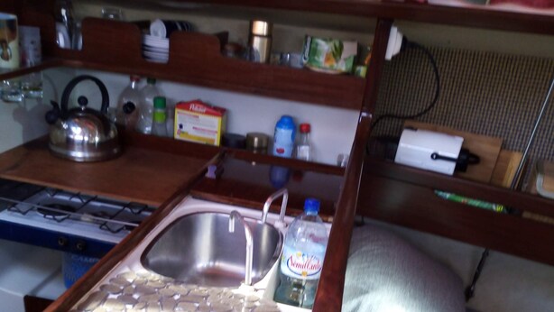 A compact kitchenette with a sink, stove, and storage cabinets.