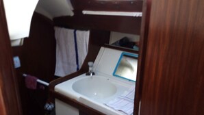 A compact bathroom with a sink, toilet, and a small window.