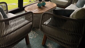 A covered outdoor seating area with wicker furniture and a view of a lake. - Designer Lake Champlain Retreat with Adirondack Views & Private Waterfront (Willsboro)