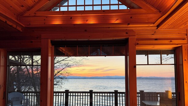 A wooden cabin with large windows overlooking a body of water and a sunset. - Designer Lake Champlain Retreat with Adirondack Views & Private Waterfront (Willsboro)