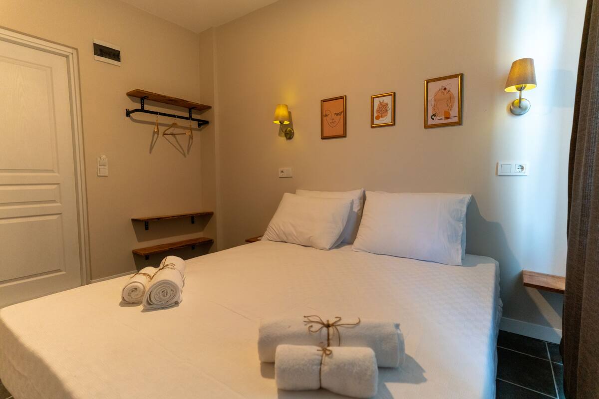 A neatly made bed with white linens, two rolled towels, and a small decorative item on the bed.