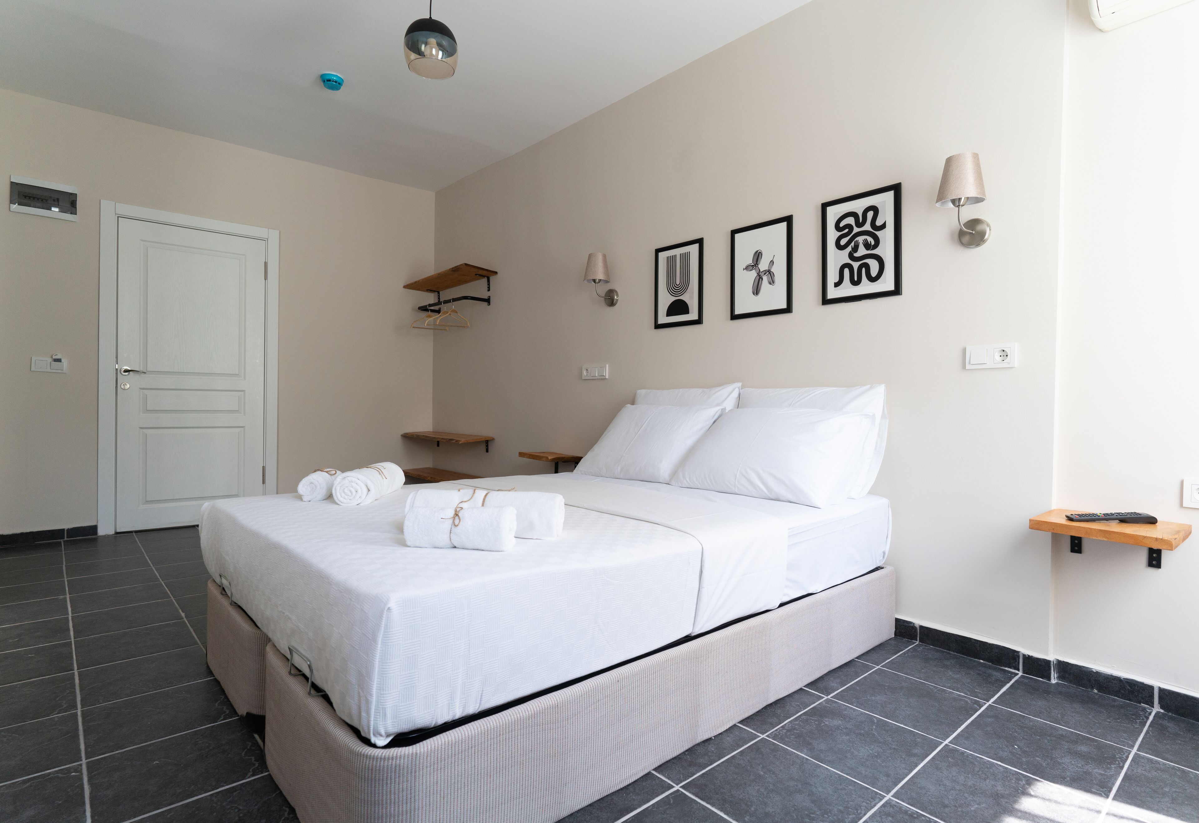 Ein ordentlich eingerichtetes Schlafzimmer mit einem Bett, Nachttischen und Wandbildern.