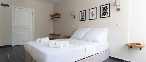 Un dormitorio ordenado con cama, mesitas de noche y obras de arte colgadas en la pared.