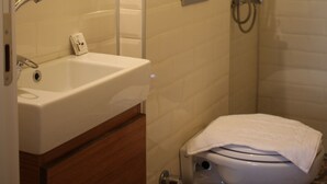 Un baño con lavamanos, inodoro y ducha blancos.