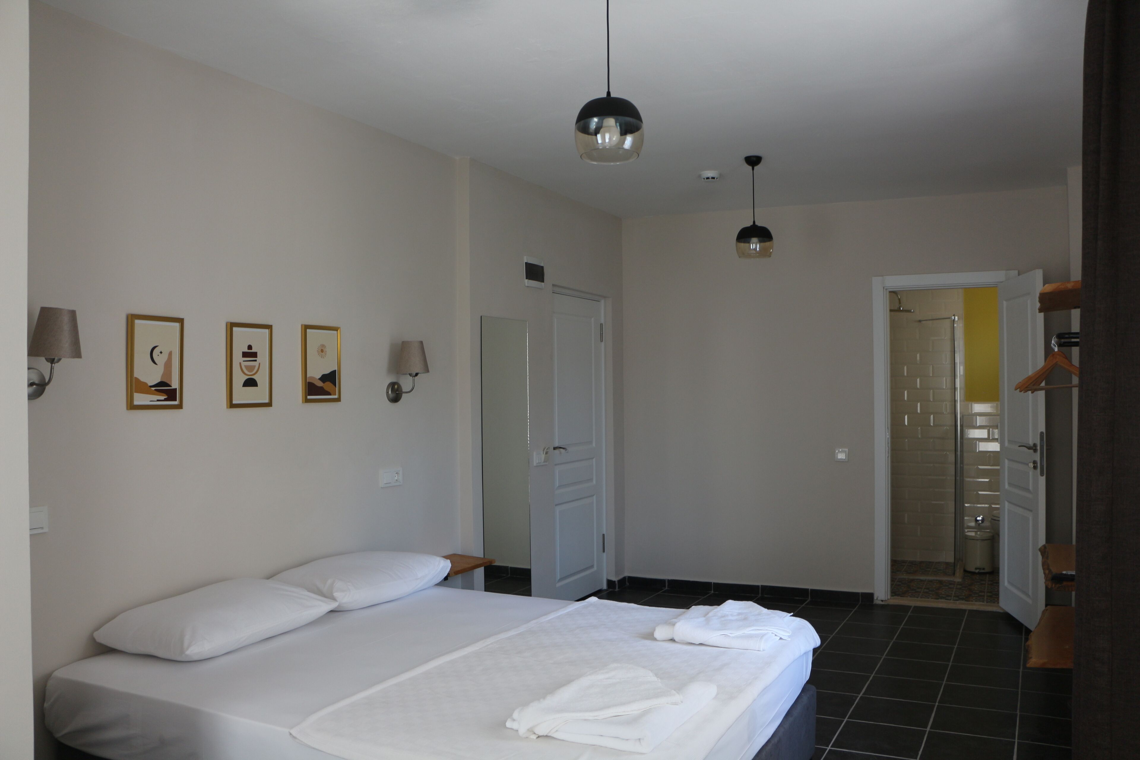 A bedroom with a bed, a door, and a hallway leading to a bathroom.