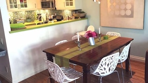 A dining area with a wooden table, white chairs, a chandelier, and a kitchen in the background. - **Mickeys Hideaway**Walk to Disneyland**Summer Fun! (Anaheim)