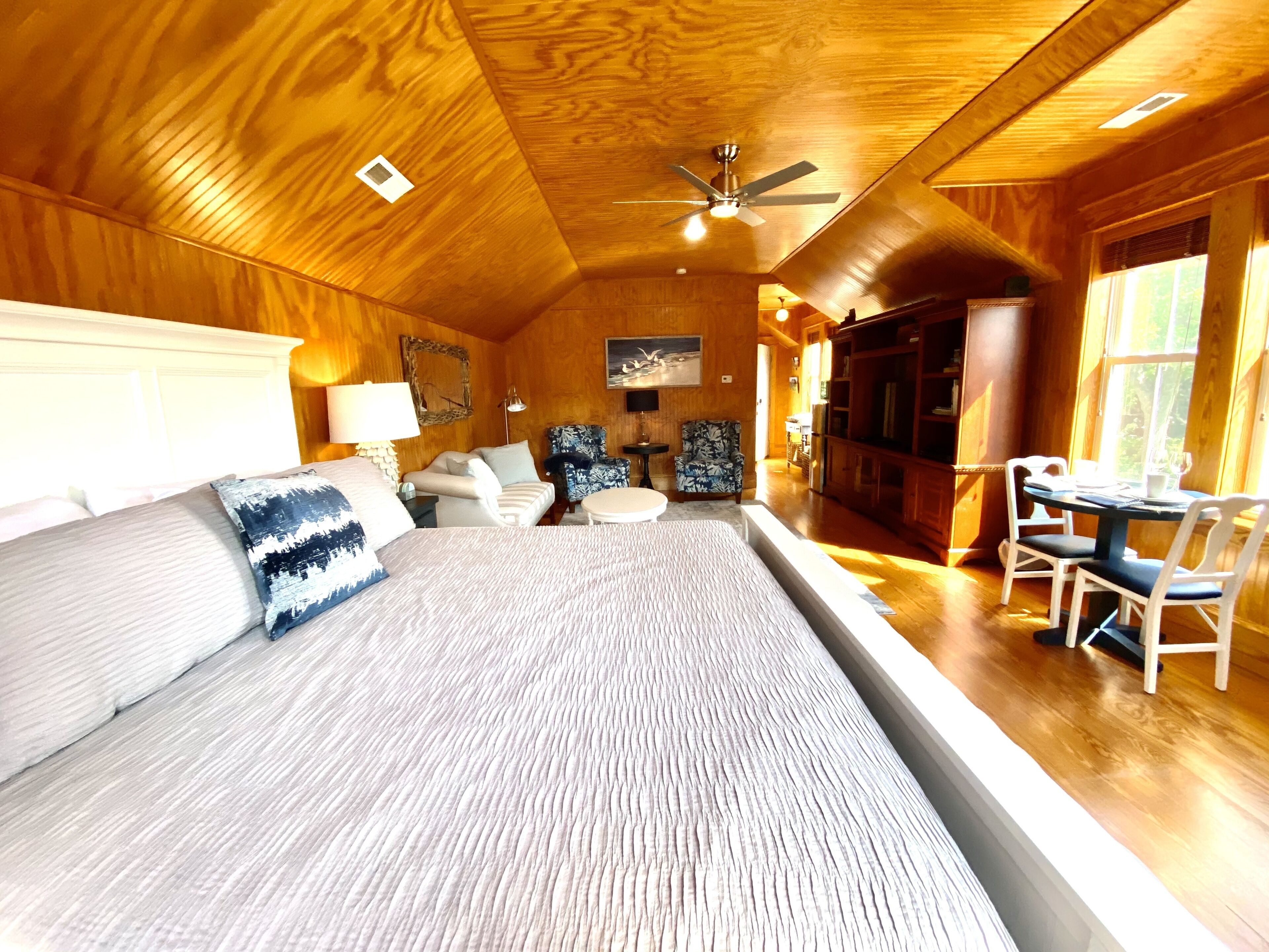 Una habitación amplia con una cama grande, una zona de comedor y un espacio de descanso con ventilador de techo.