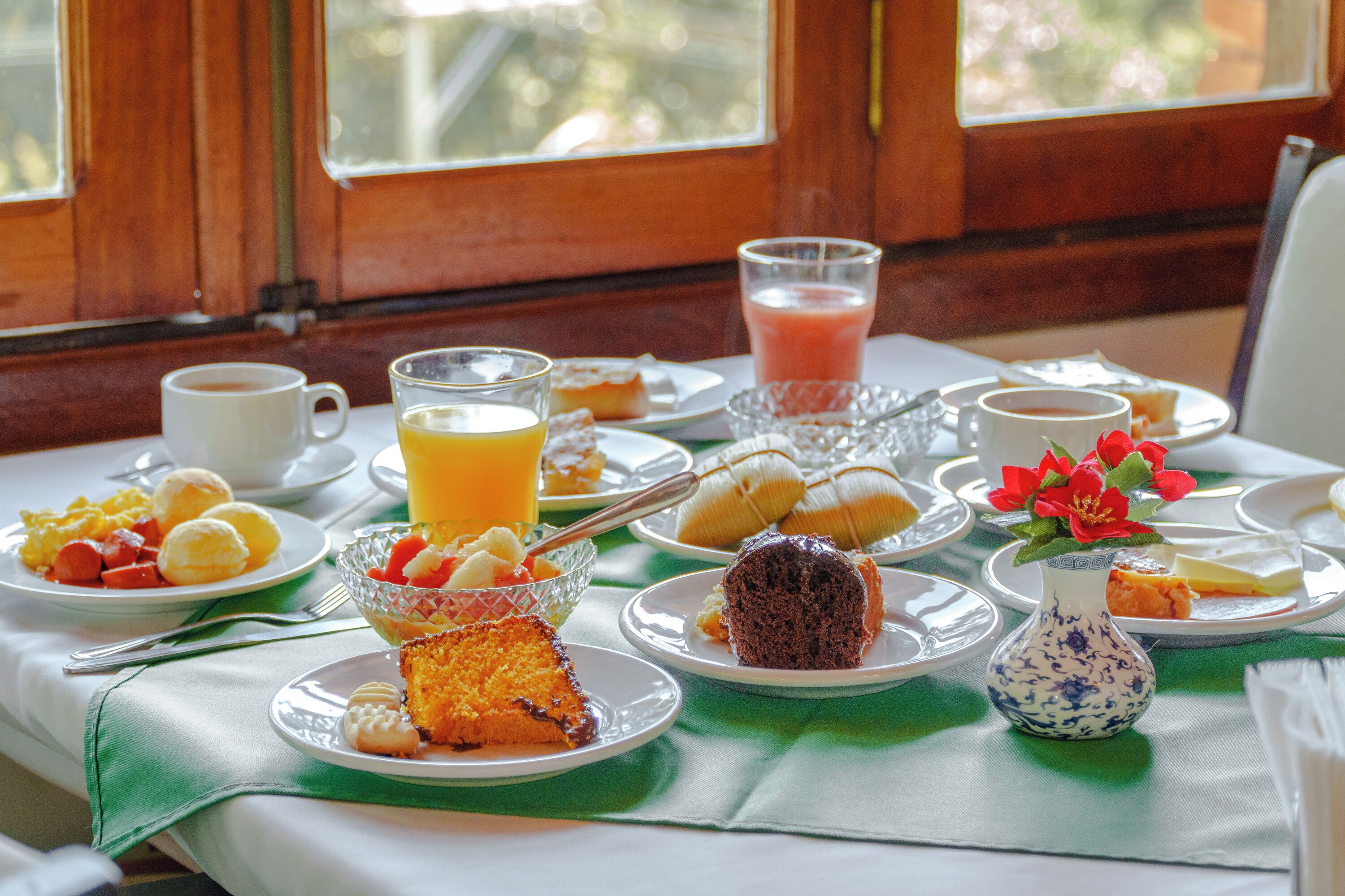Une table de petit-déjeuner avec divers plats, notamment des pâtisseries, des fruits et un vase rempli de fleurs.