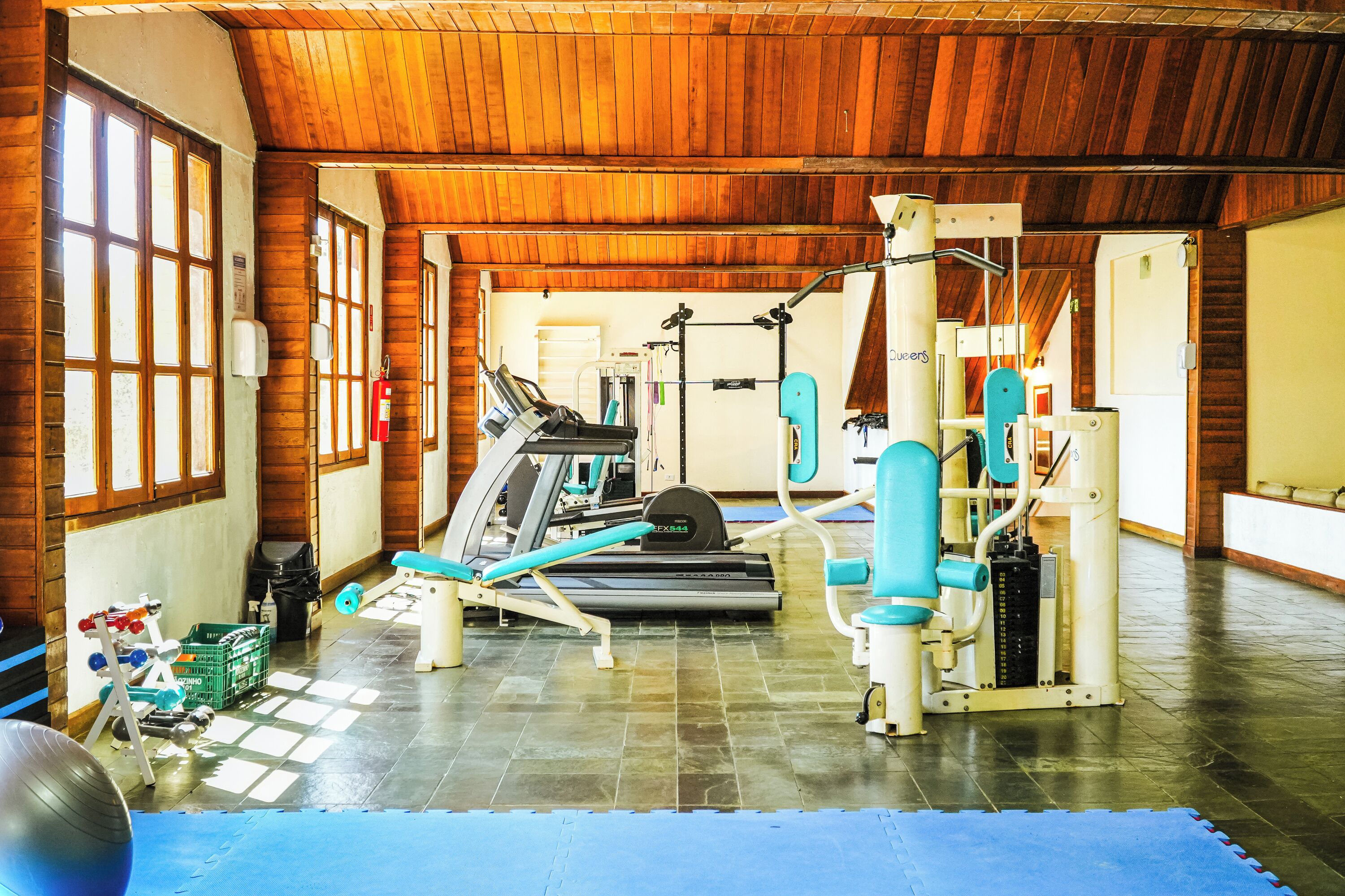 A gym with exercise equipment, a treadmill, and a blue mat on the floor.