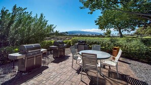 An outdoor patio with a grill, seating, and a view of a distant landscape.