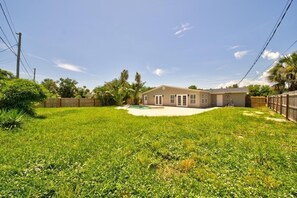 A residential property with a swimming pool, a fenced yard, and a two-story house.