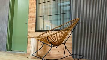 A wicker rocking chair in a room with wooden walls and a large window.