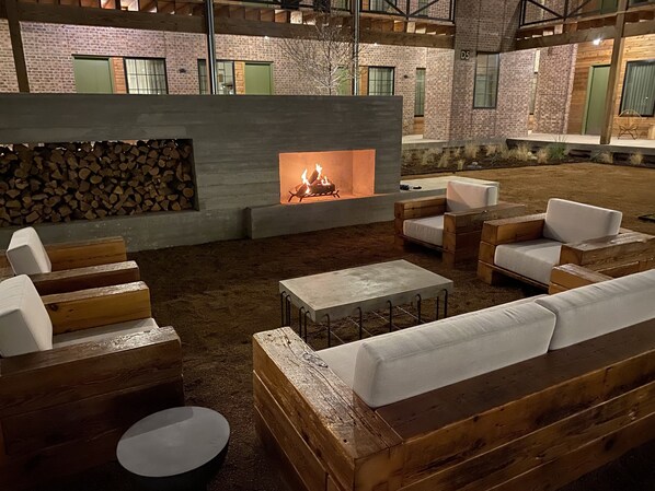 An outdoor seating area with wooden furniture and a fire pit. - Cotton Court, by Valencia Hotel Collection (Lubbock)
