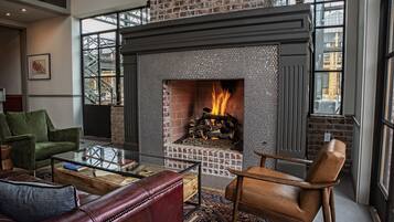 A cozy living room with a brick fireplace, leather furniture, and a glass coffee table.