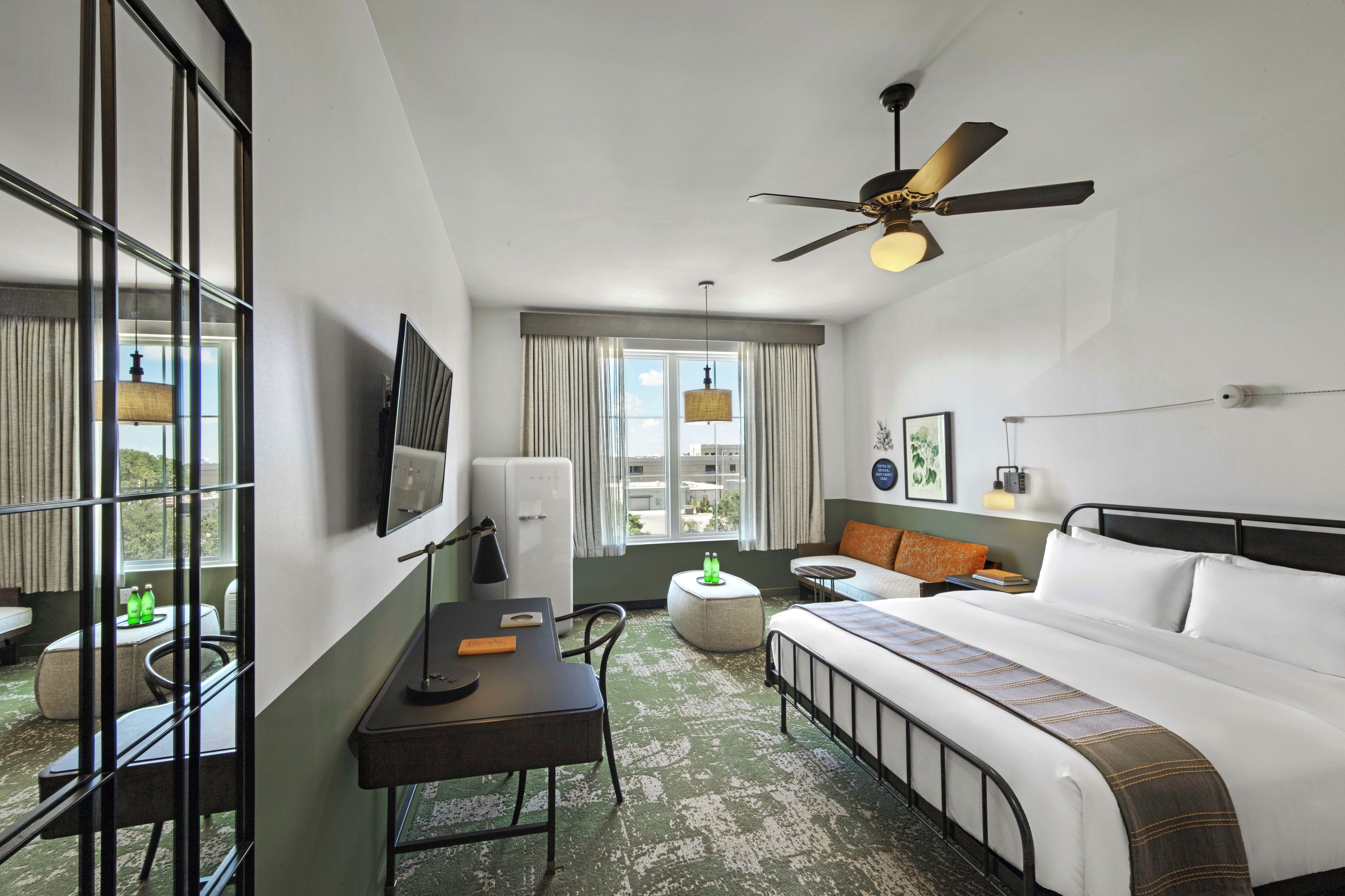 A hotel room with a bed, desk, chair, and a ceiling fan.