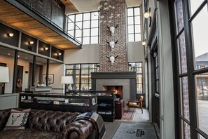 A spacious lobby with a fireplace, leather seating, and a display of shoes. - Cotton Court, by Valencia Hotel Collection (Lubbock)