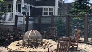 A multi-story building with a balcony, outdoor seating area with chairs, a fire pit, and a wooden fence. - Allegheny Springs Slope Side Penthouse - Amazing Views (Snowshoe)
