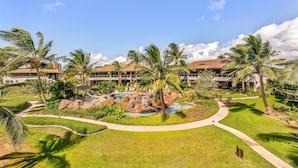 A resort with a swimming pool, palm trees, and a waterfall.