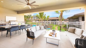 A spacious outdoor area with a dining set, a sofa, and a grill.