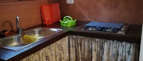Una cocina con armarios de madera, un lavamanos, una estufa a gas y una ventana.