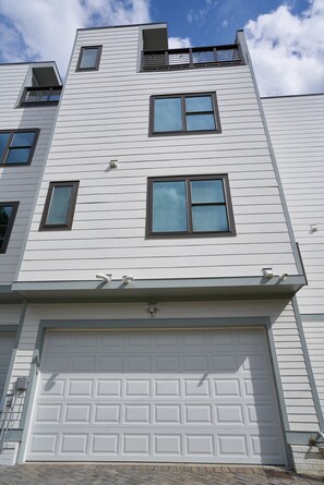 Un immeuble résidentiel à plusieurs étages, avec une façade blanche, de nombreuses fenêtres et un portail de garage.