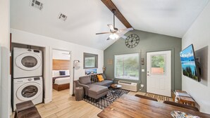 A compact living space with a dining area, a sofa, a washing machine, and a television. - GrandLake*Kayak*ForestView*Firepit*Kings*Lakefront (Grove)