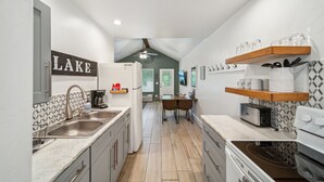 A modern kitchen with a central island, built-in appliances, and a view into the dining area. - GrandLake*Kayak*ForestView*Firepit*Kings*Lakefront (Grove)