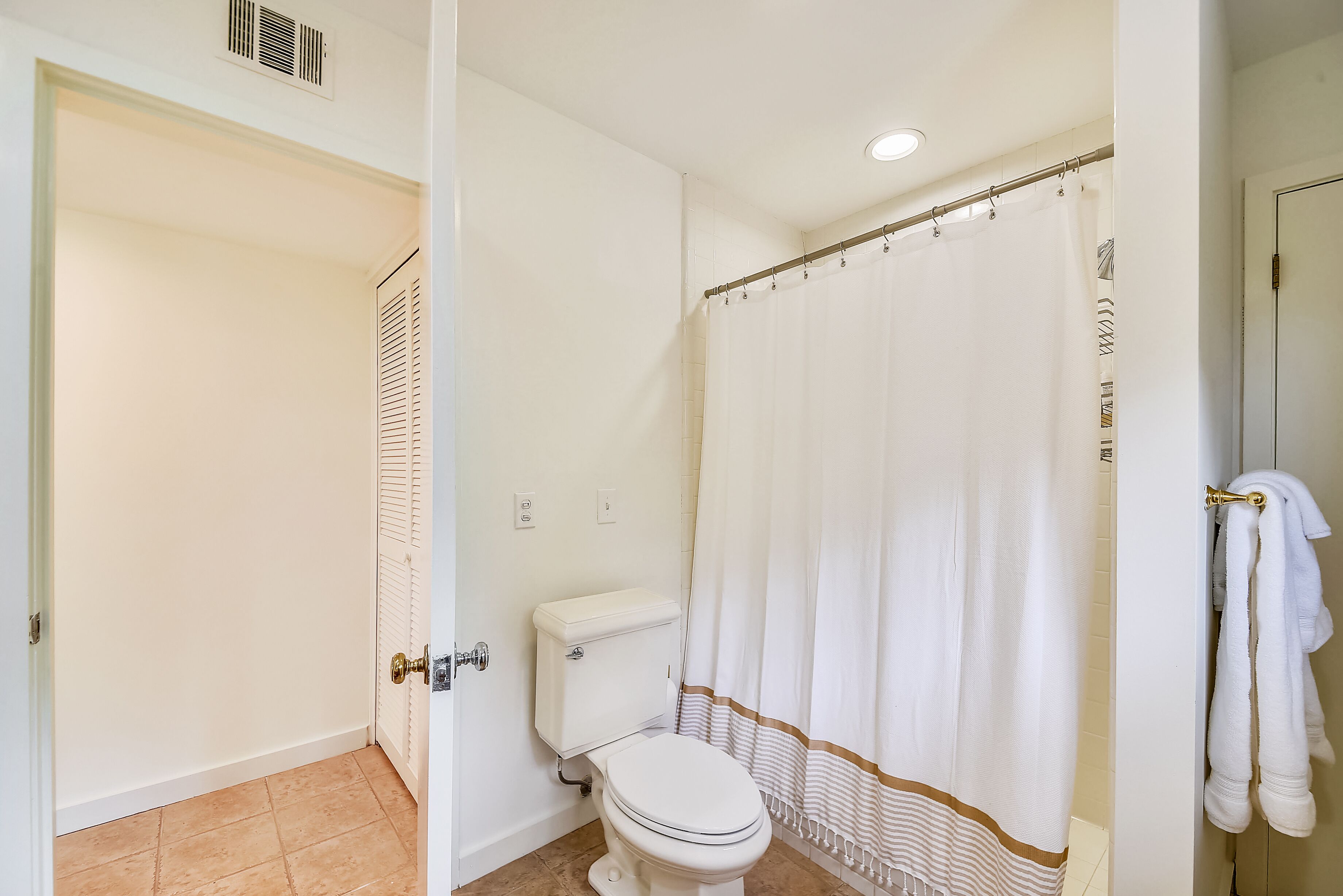 A bathroom with a toilet, shower curtain, and towels.